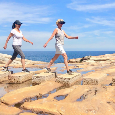 Two women walking over rocks