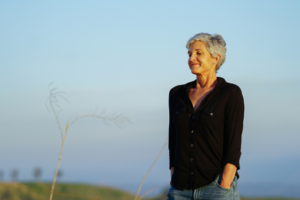 Woman with grey hair standing on hilltop
