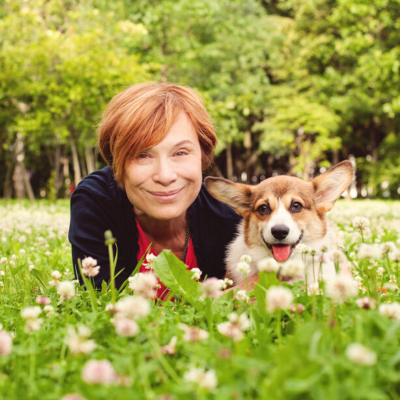 Woman in field of flowers smiling with dog