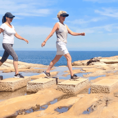 Two women walking over rocks