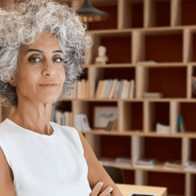 Woman with gray hair stands among shelves