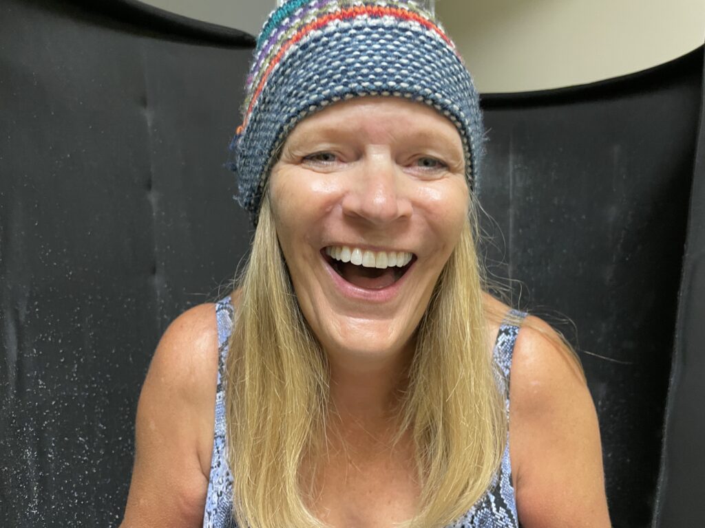 woman in bathing suit and knit hat laughing