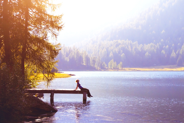Woman sitting on dock of lake