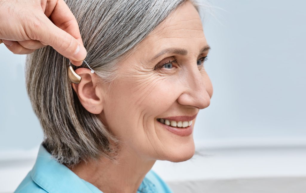 Close-up of hearing aid near senior female patient's ear