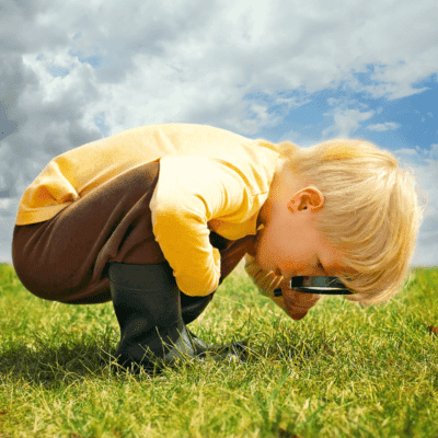 little boy looks through magnifying glass